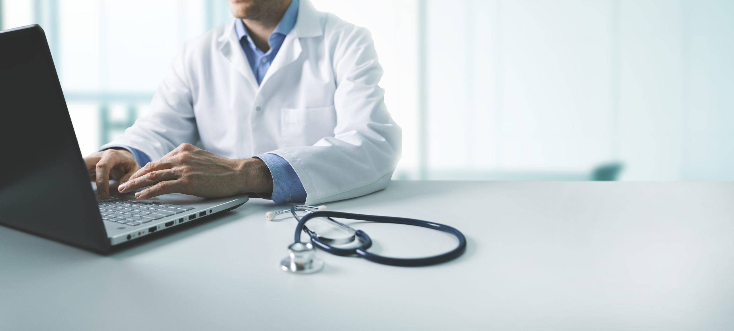online medical consultation &#8211; doctor working on laptop computer in clinic office. copy space
