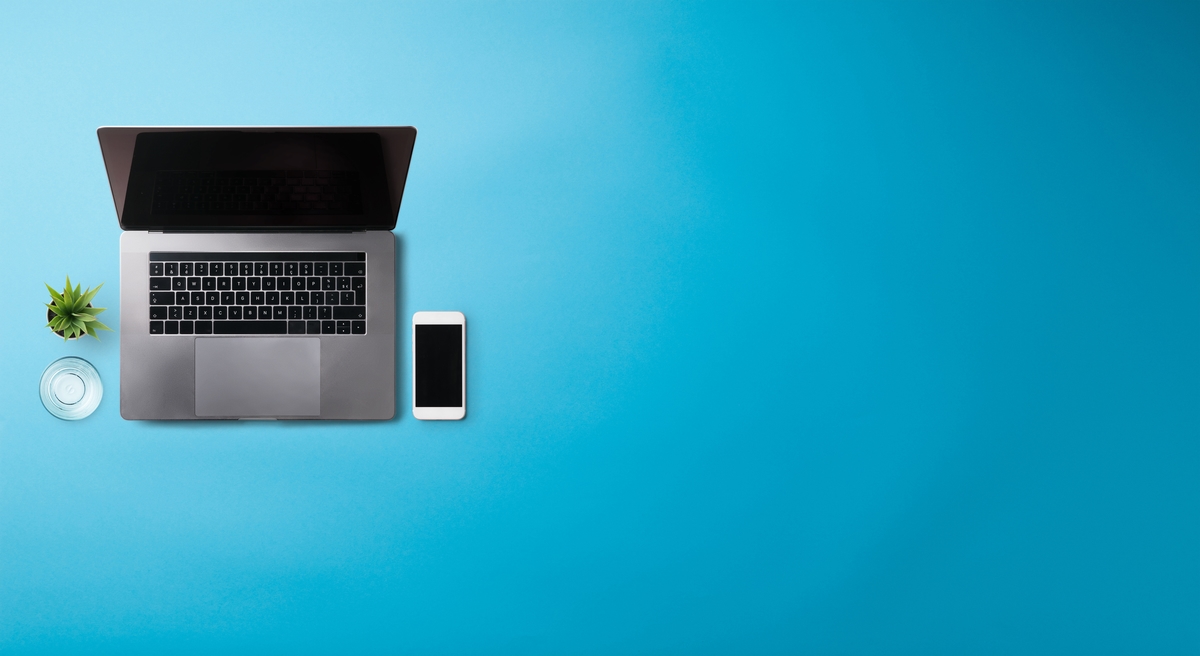 Flat lay top view office desk working space with laptop on blue background. Copy space.