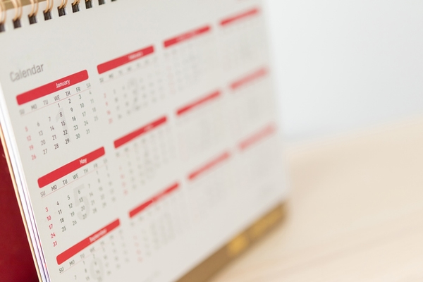 Calendar page close up on wood table with white wall background business planning appointment meeting concept