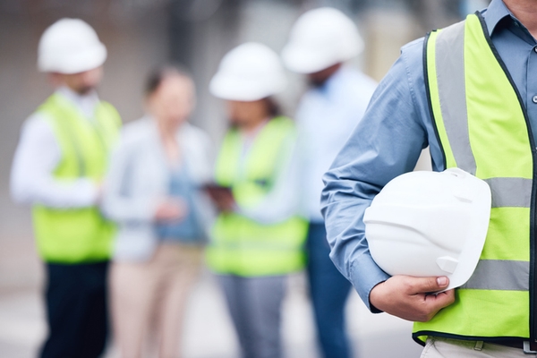 Shot of an unrecognizable architect holding a helmet at a building site