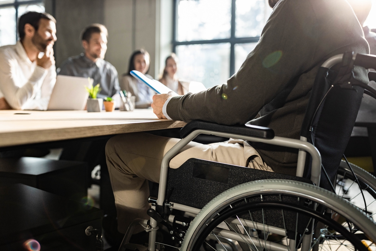 Unrecognizable businessman in wheelchair having a meeting with his colleagues.