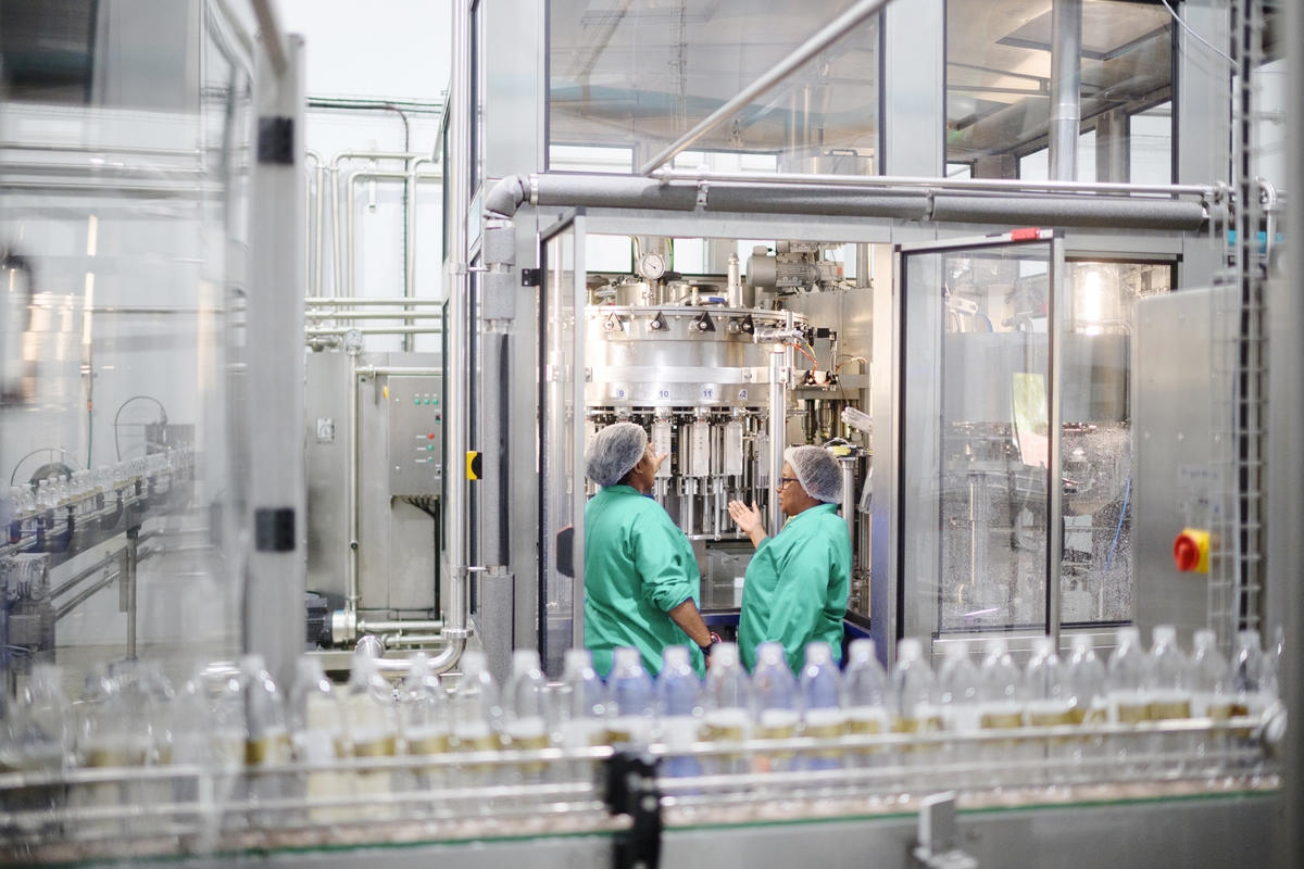 Two Female Operators at an Automatic Water Filling Machine in Water Bottling Plant