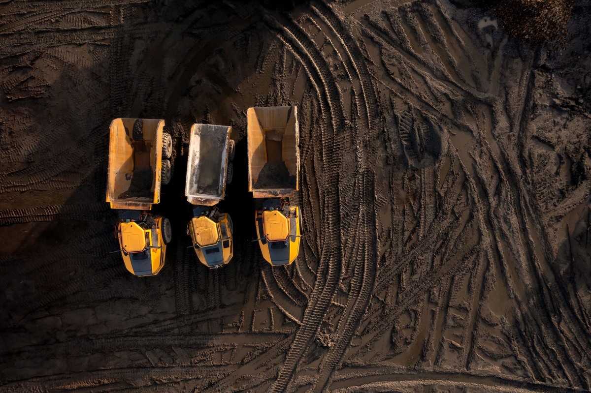 Aerial view above earth mover trucks on a muddy construction site
