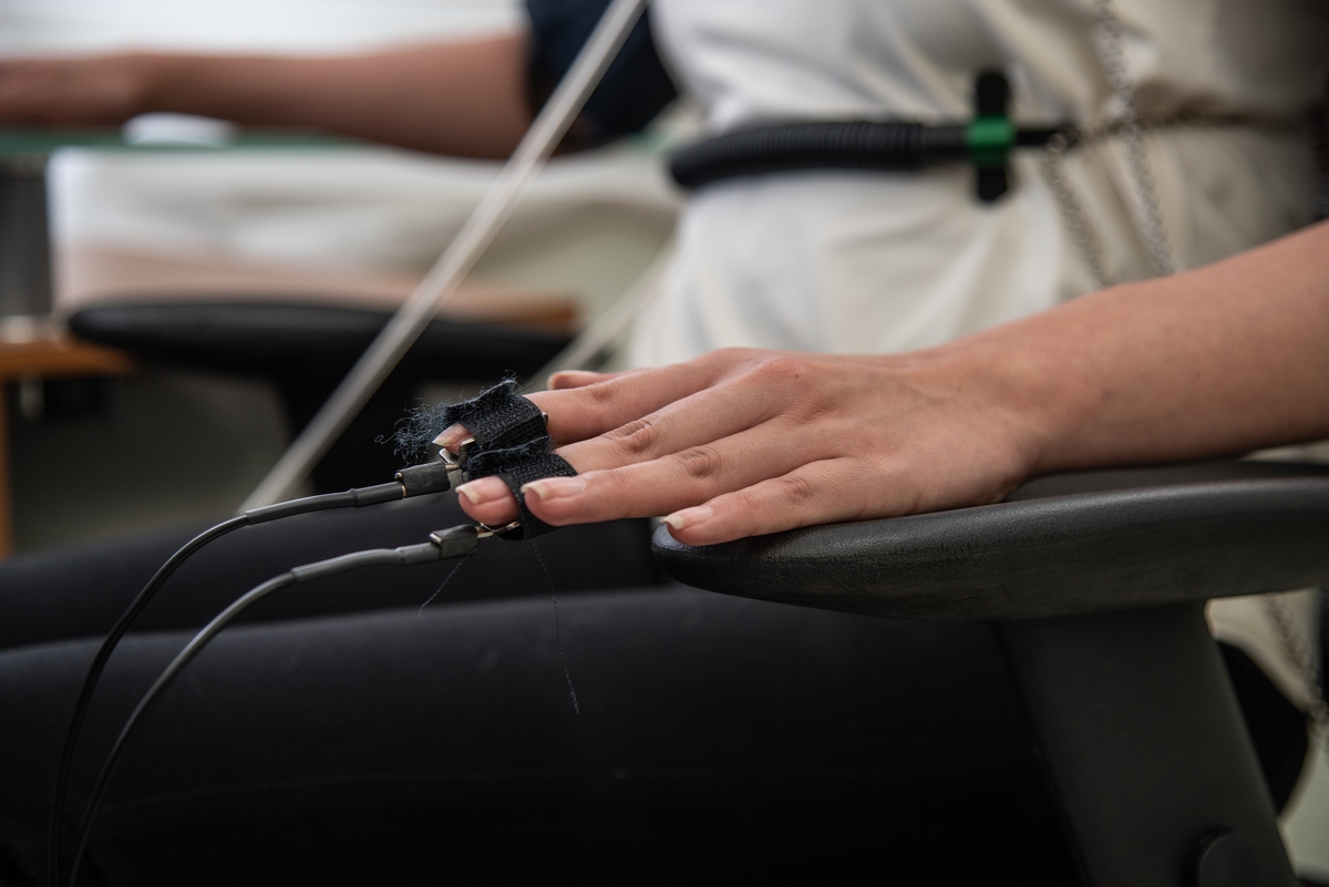 Professional integrity examination: Latina woman in a white blouse undergoes polygraph testing with sensors on fingers and body.