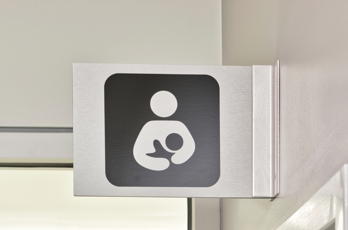 Nursing Room sign made of metal, above a doorway in an office environment.