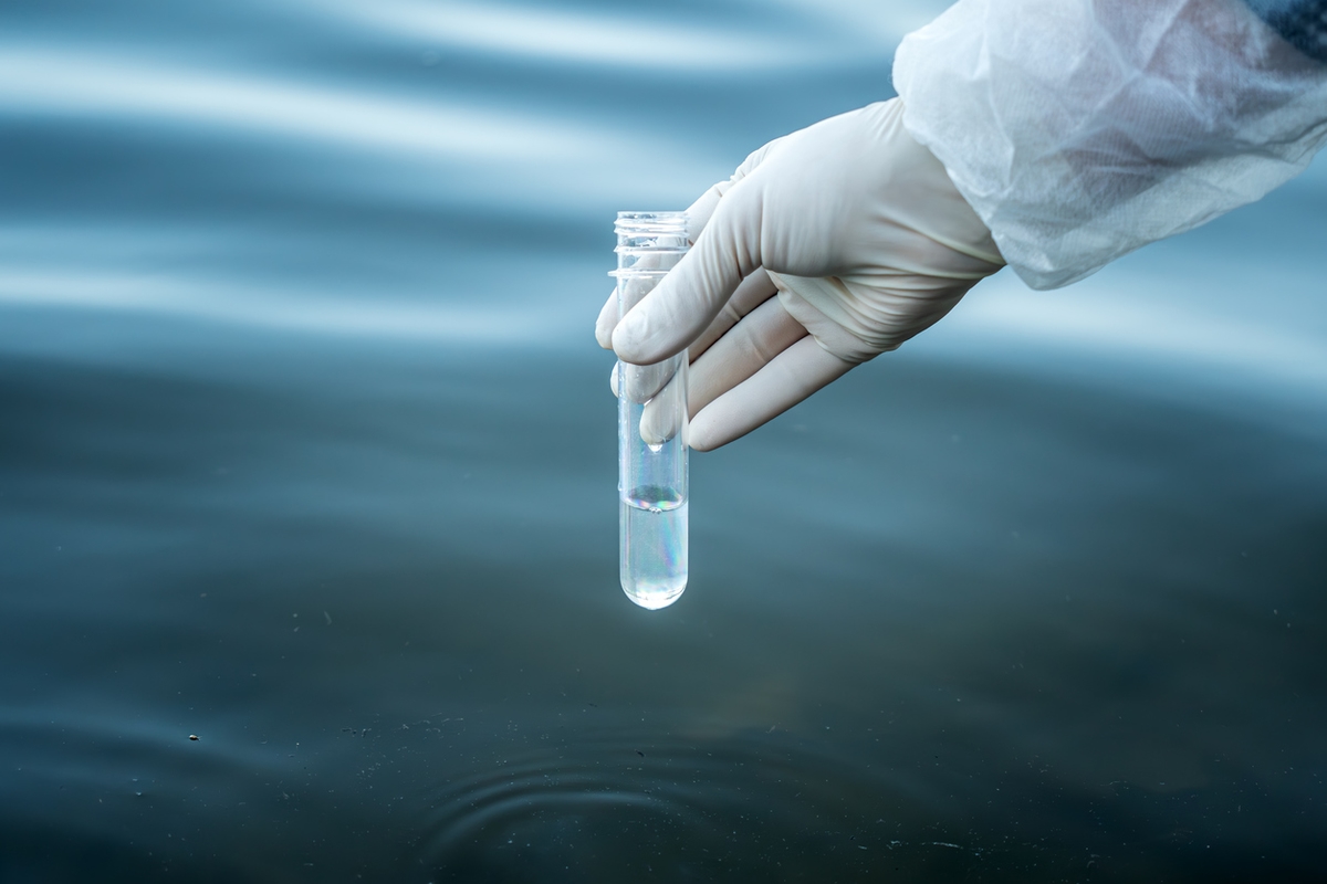 examination of water quality in natural reservoir. test tube in a man&#8217;s hand with water to check its purity.