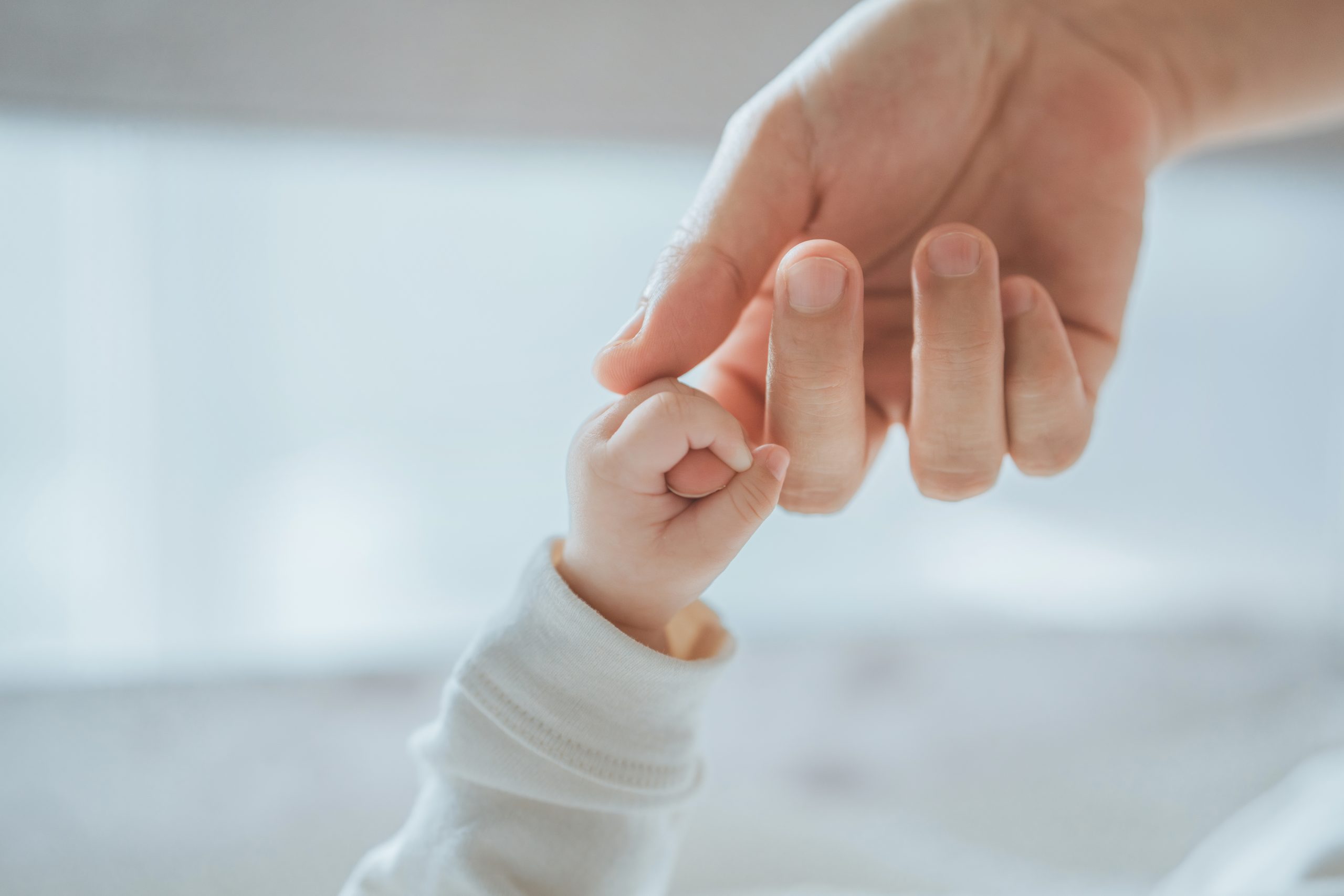 Close-up little hand of child baby holding hand of mother, A newborn holds on to mom&#8217;s, dad&#8217;s finger, Love and relationship with infant, Care and support, Dreaming and protection