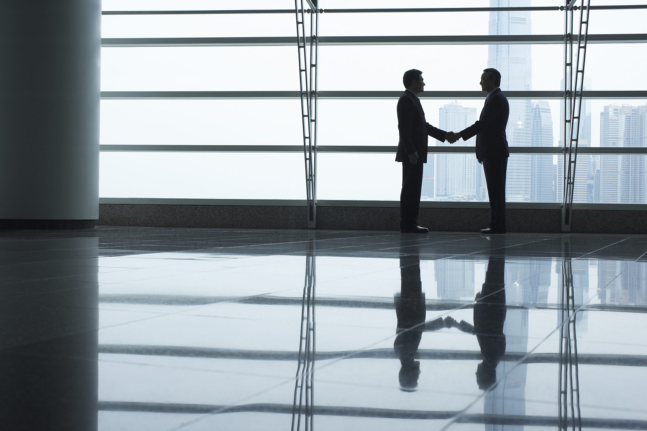 Businessmen Shaking Hands In Airport Terminal
