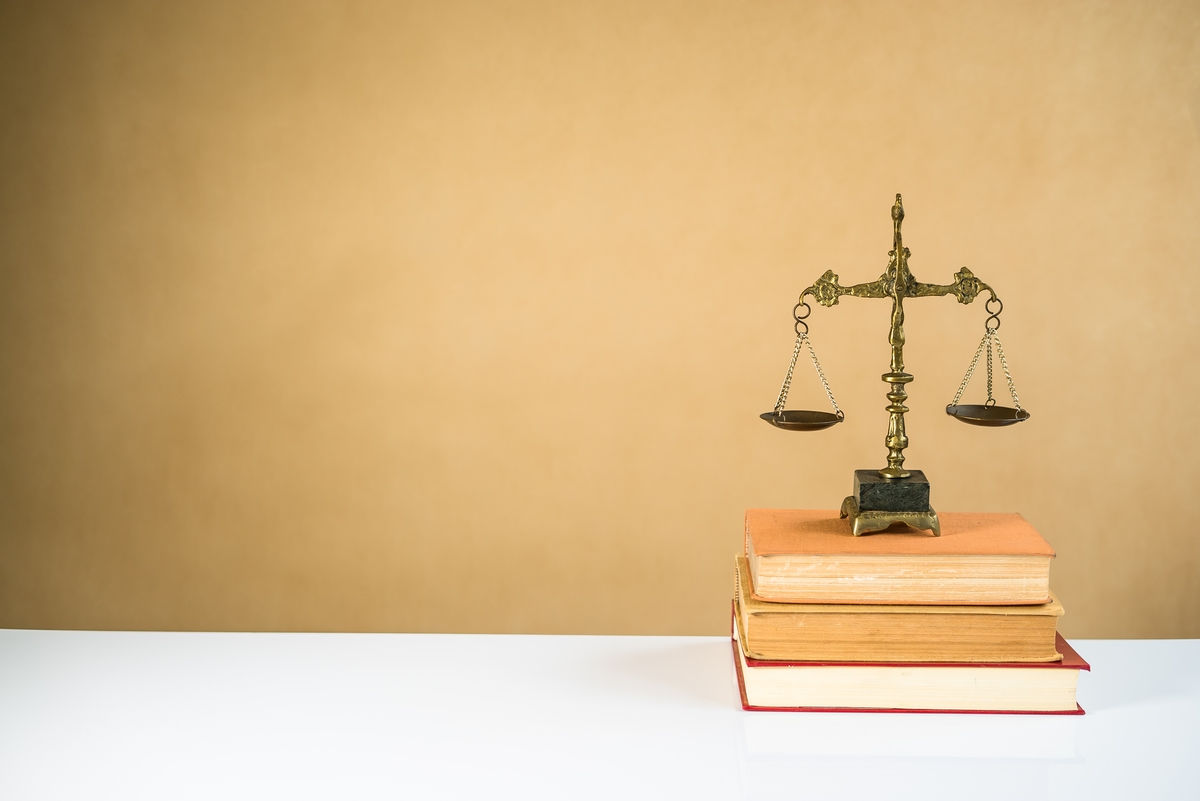 Law and Justice concept. Mallet of the judge, books, scales of justice. Gray stone background, reflections on the floor, place for typography. Courtroom theme.