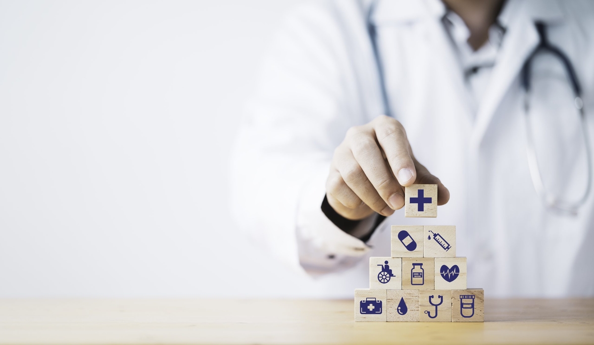 Doctor putting and stacking wooden block cube which print screen health care and medical icons for healthy and wellness concept.