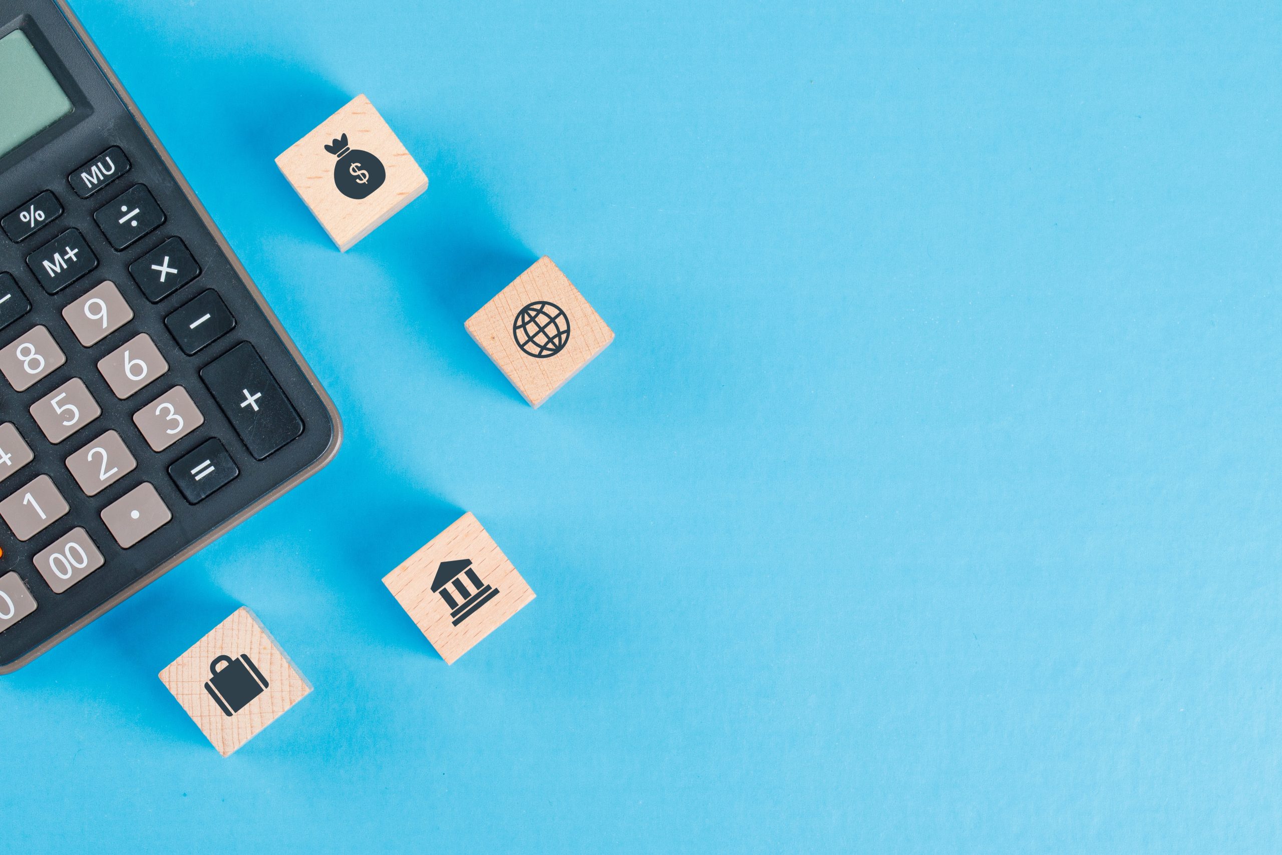 concepto-financiero-con-iconos-en-cubos-de-madera-calculadora-en-mesa-azul-plano-lay